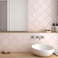 a white bowl sink sitting on top of a wooden counter next to a bathroom mirror