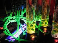 three vases with neon lights in them on a table