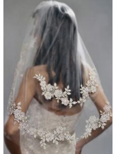 the back of a bride's wedding dress, with veil and flowers on it