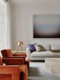 a living room filled with furniture and a painting on the wall