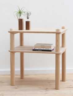 a wooden table with two books on it and a plant in the corner next to it