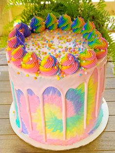 a cake with rainbow icing and sprinkles on it sitting on a table