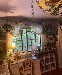 a kitchen with lots of plants hanging from the ceiling, and a desk in front of a window