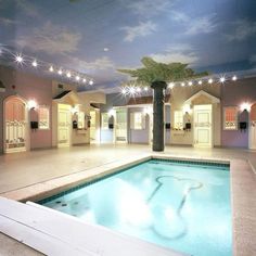 an indoor swimming pool with lights and palm tree in the center, surrounded by white doors