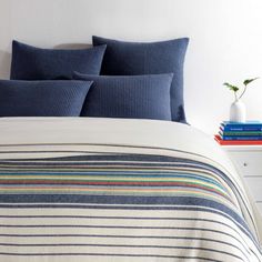 a bed with blue and white striped comforter next to two books on a nightstand