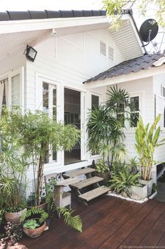 a white house with potted plants on the front porch and stairs leading up to it