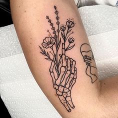 a woman's arm with flowers on it and a hand holding something in the middle