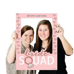 two women holding up a pink photo frame with the words bride squad written on it