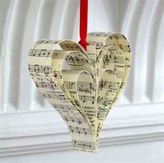 a heart shaped ornament hanging from a red string with sheet music notes on it