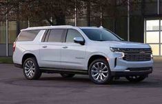 the new chevrolet suburban suv is parked in front of a large building with glass doors