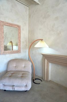 a living room with a chair, lamp and mirror on the wall next to it