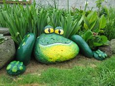 a frog statue sitting in the grass next to some plants