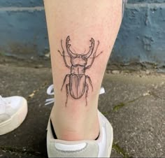 a tattoo on the leg of a woman with a beetle in it's center