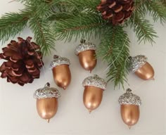 christmas ornaments hanging from a tree with pine cones and glittered acorns on them