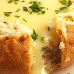 a bread bowl filled with cheese and sauce on top of a white plate, ready to be eaten