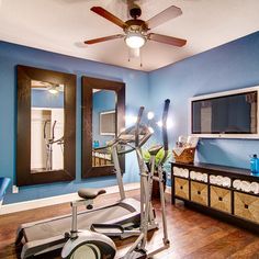 an exercise room with blue walls and wooden floors