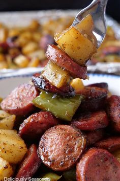 a fork with some food on it in the middle of a pile of potatoes and peppers