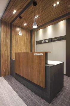 the reception desk is made of wood and has lights hanging from it's ceiling