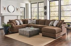 a living room filled with lots of furniture next to large windows and wooden flooring