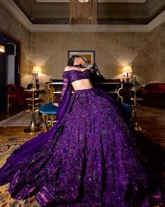 a woman in a purple dress is standing near a piano