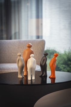 three small figurines are sitting on a table in front of a couch and window