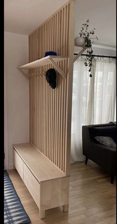 a wooden shelf with a hat on it in front of a black chair and window