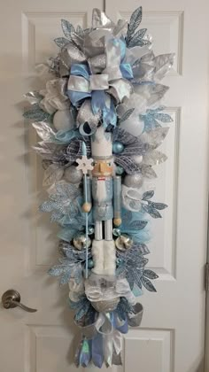 a christmas wreath hanging on the front door with blue and silver decorations, snowflakes and angel wings