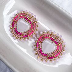 pair of pink and gold beaded earrings on white plate with blue cloth in background