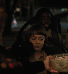 a group of people standing next to each other near a bowl of food on a table