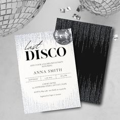 a black and white wedding card with disco balls on the table in front of it