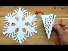 someone is cutting out a snowflake from paper