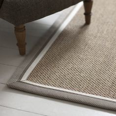 a close up of a rug on the floor with a wooden bench in the background