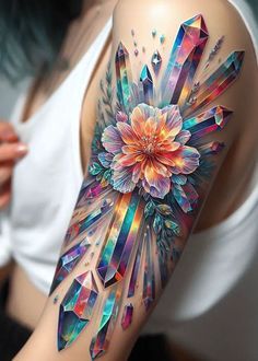 a woman's arm with an artistic tattoo design on it, featuring crystals and flowers