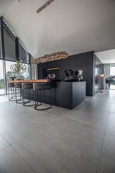 a modern kitchen with an island counter and bar stools in front of large windows