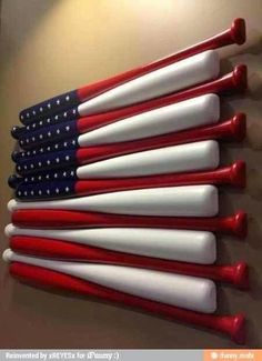 red, white and blue baseball bats lined up against a wall in the shape of an american flag