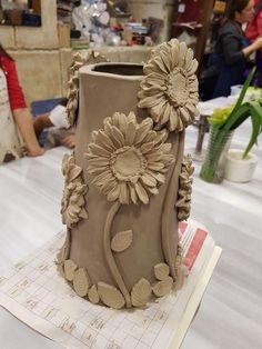 a clay vase with sunflowers is on display