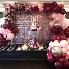 a table with balloons and candles in front of a wall that has flowers on it