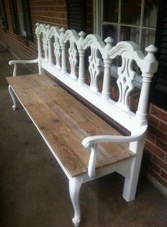 a white bench sitting in front of a window on the side of a brick building