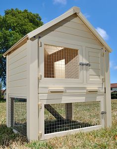 a large white chicken coop in the grass