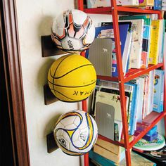 three soccer balls are hanging on the wall next to a bookshelf and ladder