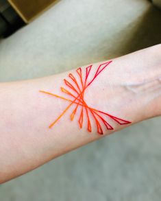 a person's arm with an orange and red tattoo on it