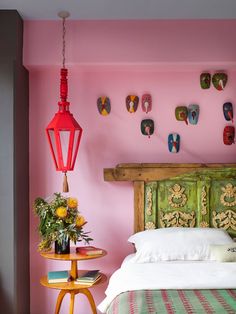 a bedroom with pink walls and green headboard, white bedding, yellow side table