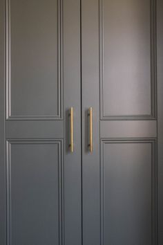 two gold handles on the doors of a gray closet