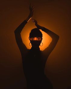 a woman with her hands up in the air while wearing a black mask and earrings