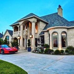 a red sports car is parked in front of a large house with columns and pillars