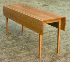 a small wooden table sitting on top of a cement floor in an empty room with no one around it