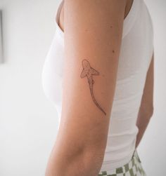 a woman's arm with a tattoo on it that has a small fish on it