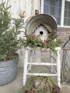 an old chair is decorated with pine cones and greenery for christmas outside the house