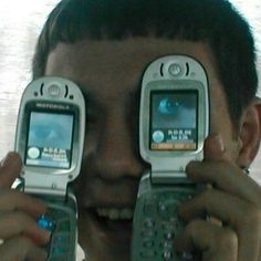 a man holding two cell phones up to his eyes