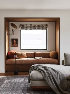 a living room with a couch, window and rug on the floor in front of it